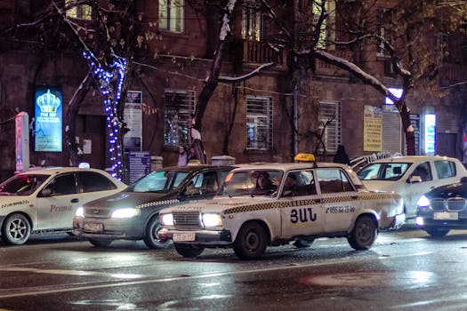 Urban nighttime scene showing taxis, traffic, and city lights on a bustling street.