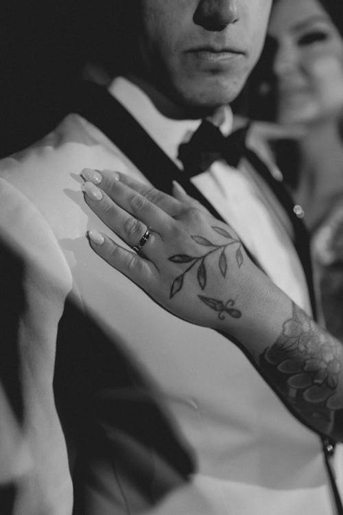 A man with tattoos on his hand and a woman with a ring on her finger