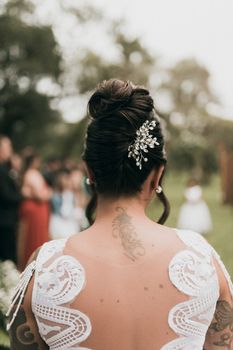 Bride with an elegant updo hairstyle adorned with jewel hairpiece outdoors at a wedding.