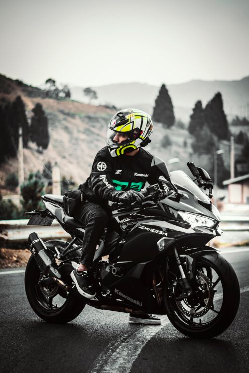 Free A biker on a Kawasaki Ninja motorcycle on a scenic highway, captured in a vertical shot. Stock Photo