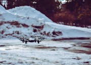 一架无人机在模糊的冬季背景中，于雪地上空徘徊