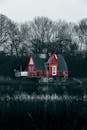 A red house on a lake with trees in the background