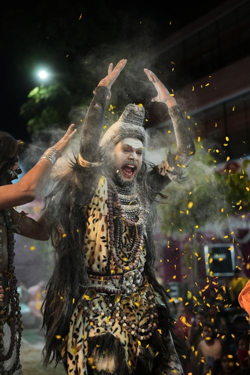 Free Man in elaborate costume performing with powder and petals at night festival. Stock Photo