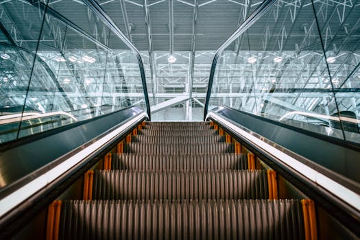 Low angle shot of a modern escalator inside a building, featuring steel framework and glass panels.