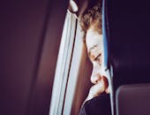 在特写肖像中，一个年轻人若有所思地看着飞机窗外