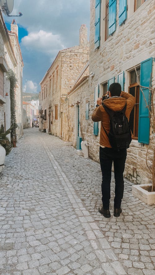 A man is walking down a cobblestone street