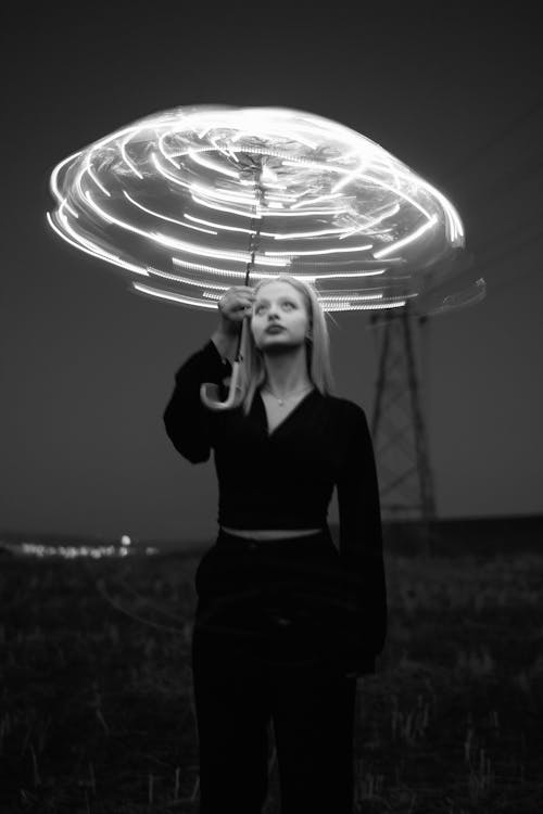 A woman holding a light up umbrella in the dark