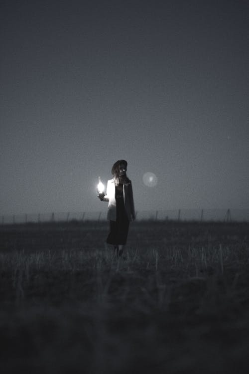 A person standing in a field holding a light