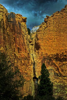 在黑暗的暴风雨天空下，雄伟的峡谷悬崖呈现出充满活力的色调