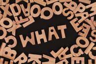 Artistic arrangement of wooden letters spelling 'WHAT' on a black background, offering creative inspiration.