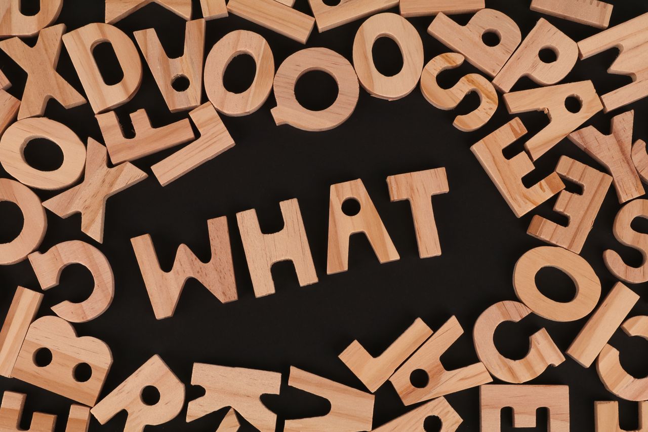 artistic arrangement of wooden letters spelling what on a black backgr