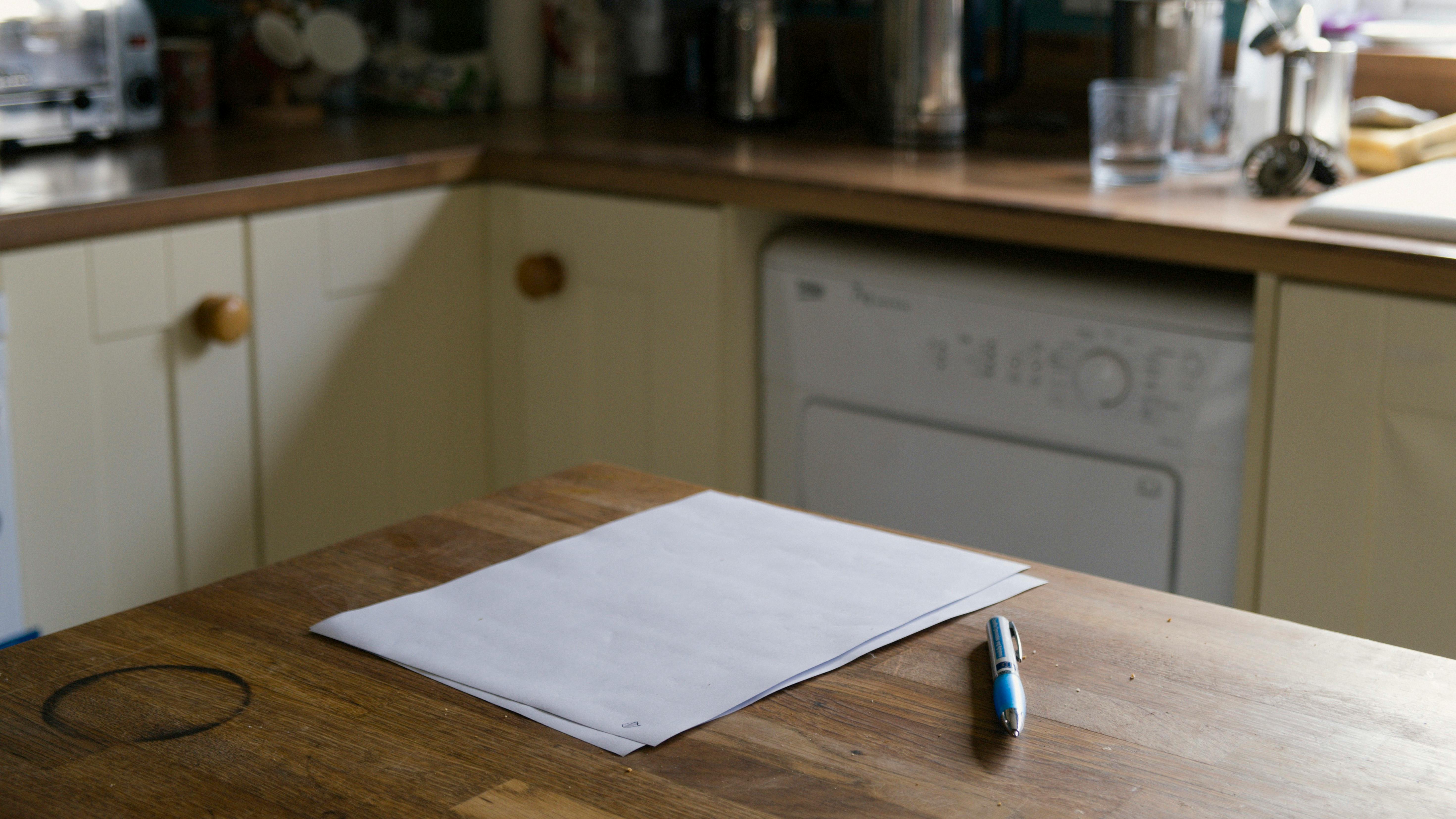 A serene kitchen scene featuring a blank paper and pen on a rustic wooden table, perfect for writing ideas.
