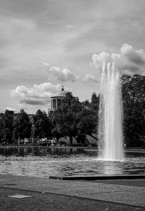 A black and white photo of a fountain in the park