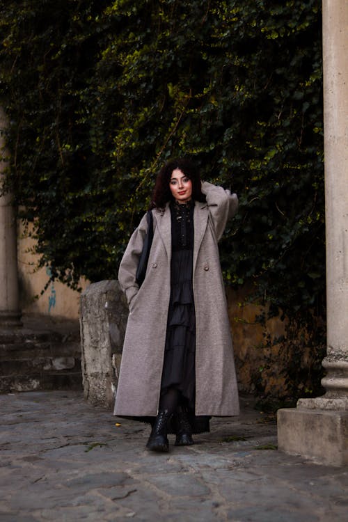 A woman in a long coat standing on a street