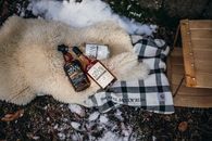 Warm winter scene with rum bottles on blanket outdoors, perfect for cozy evenings.