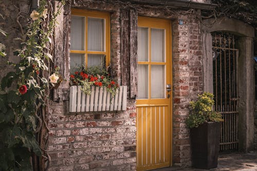 A yellow door and window in front of a brick building