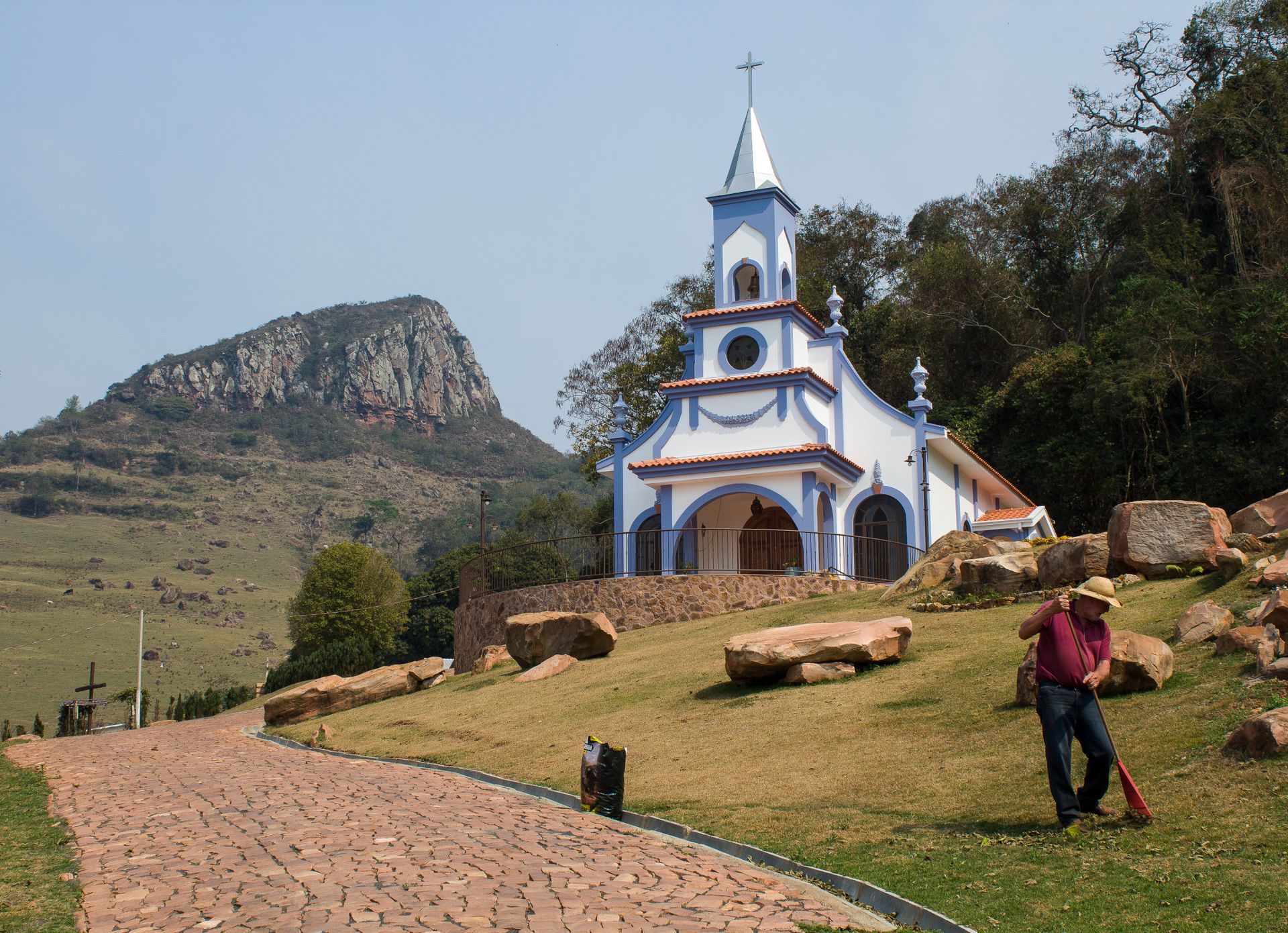 A beautiful chapel set against the mountains in Ribeirão Claro, Brazil. Serene path and sunny landscape.