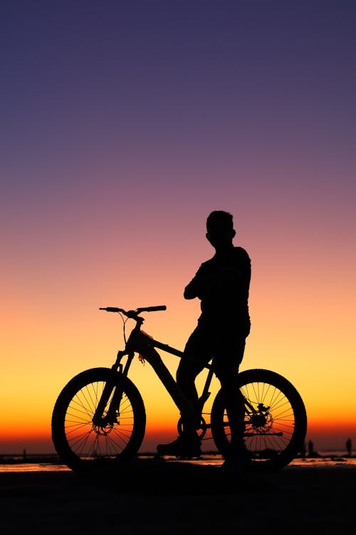 Silhouetted man with bicycle in the evening 