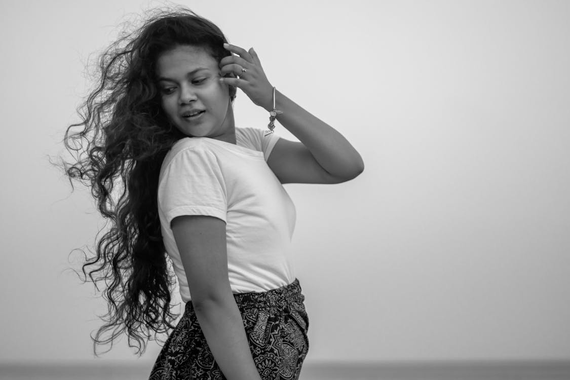 A woman with long hair is standing in front of a black and white photo