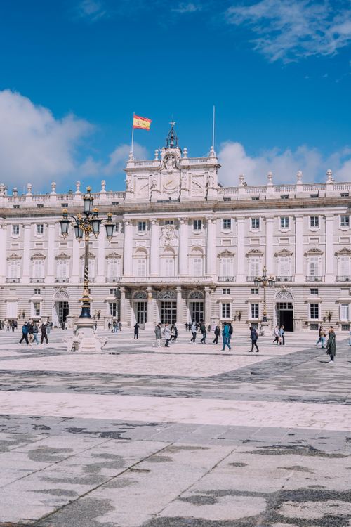Free Royal Palace of Madrid with tourists under a clear blue sky. Stock Photo