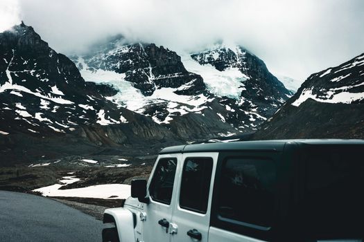 Explore the rugged beauty of Jasper, Alberta with this captivating image of a snowy mountain landscape and SUV.
