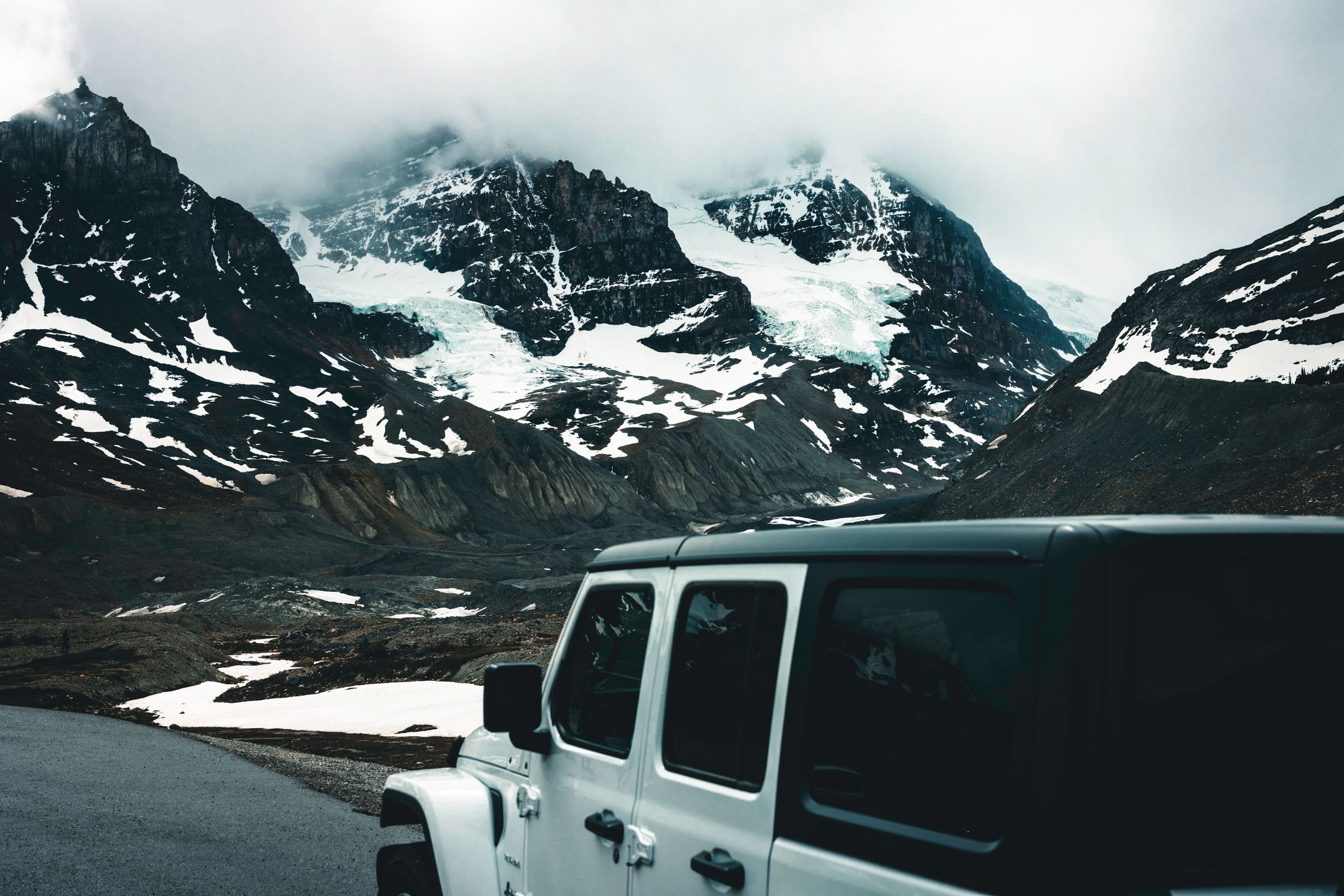 Explore the rugged beauty of Jasper, Alberta with this captivating image of a snowy mountain landscape and SUV.