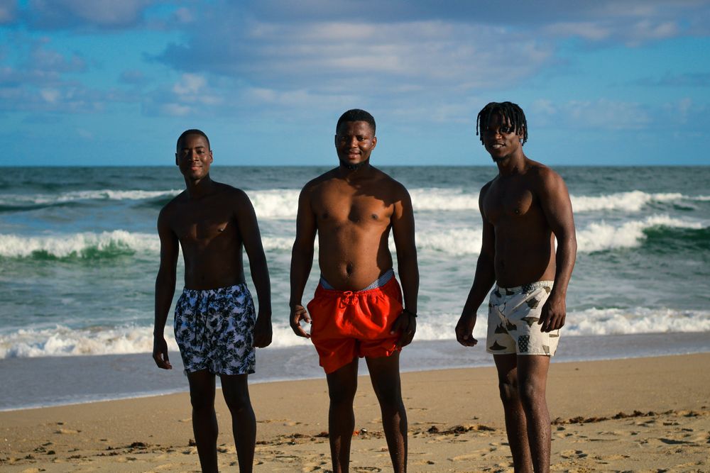 Friends standing together on a sandy beach by the ocean