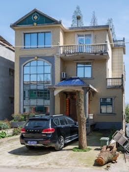 A modern three-story suburban home with an SUV parked in the driveway.