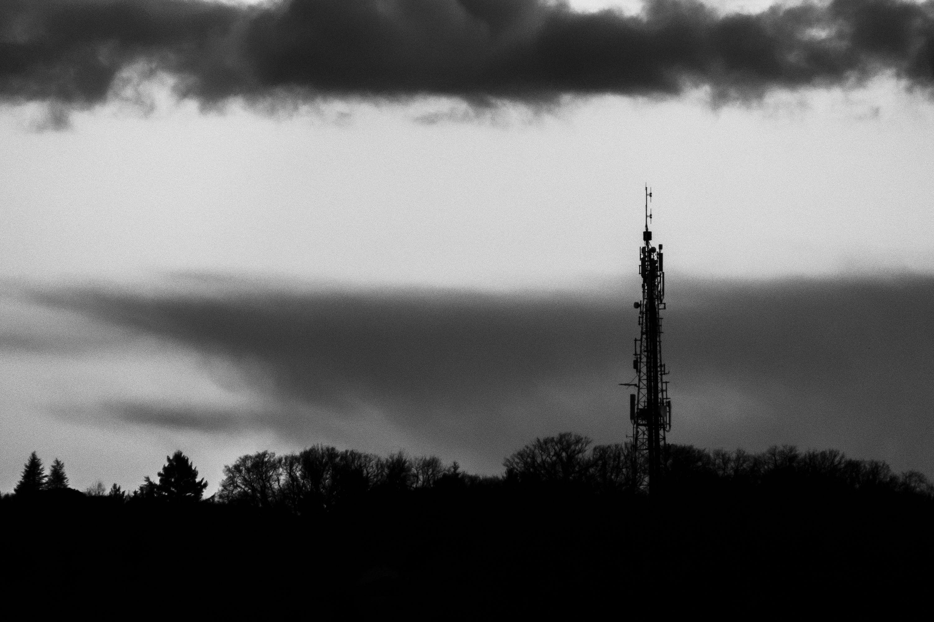 A black and white photo of a tower with clouds · Free Stock Photo