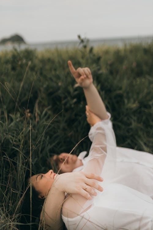 Free A couple laying in the grass with their hands up Stock Photo