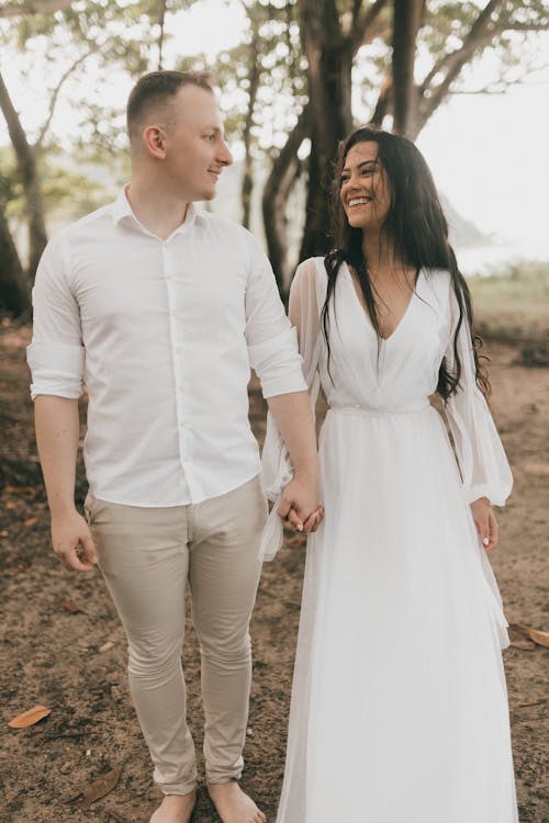 Free A man and woman in white dresses walking through the woods Stock Photo