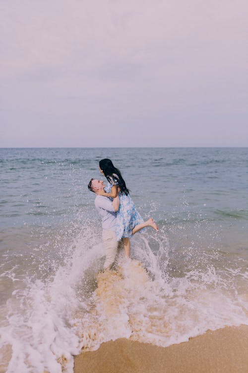 Free A couple is standing in the water at the beach Stock Photo