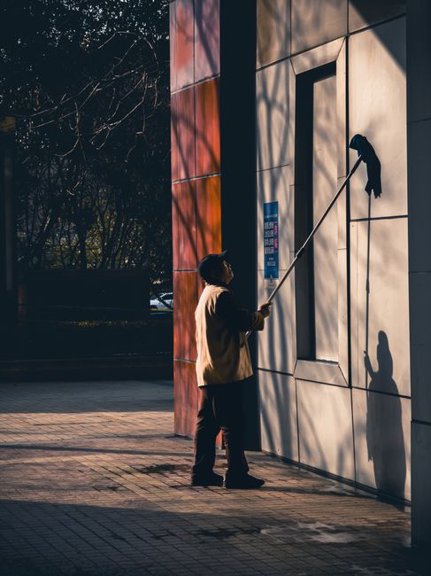 A man cleans the exterior of a building in a city, capturing a moment of urban maintenance. A man cleans the exterior of a building in a city, capturing a moment of urban maintenance.