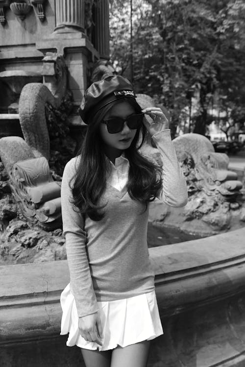 A woman in a hat and sunglasses is posing for a photo