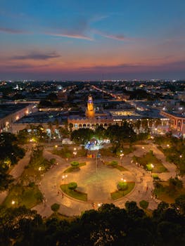 Stunning aerial view of Mérida, México during sunset, showcasing the illuminated city square and urban skyline.