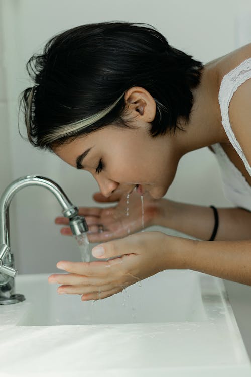 무료 물으로 그녀의 얼굴을 세척하는 여자 스톡 사진
