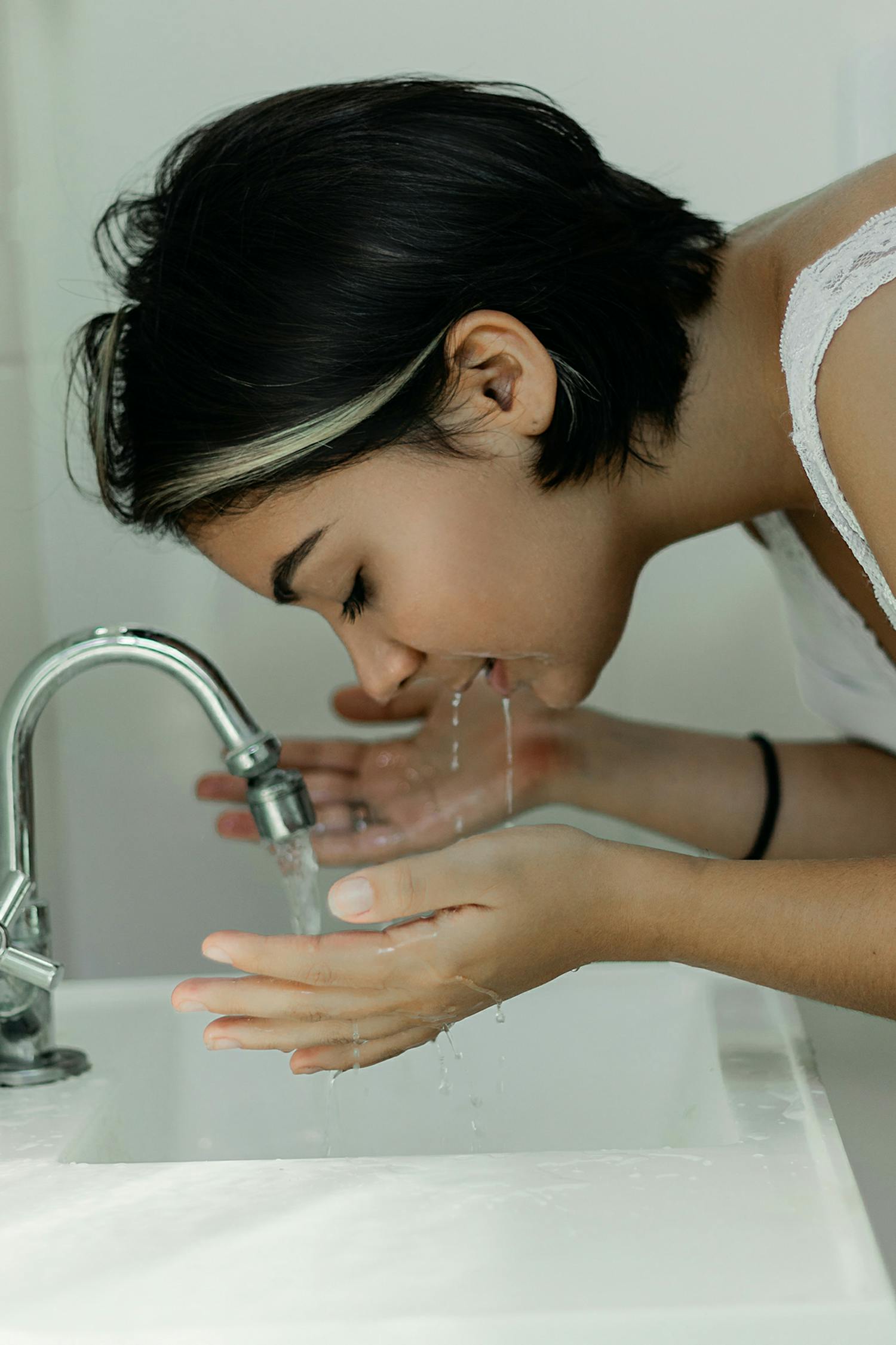 水で顔を洗う女性