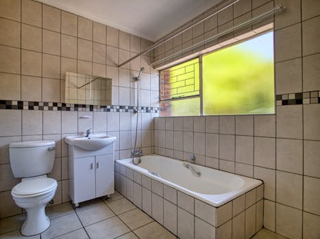 Spacious bathroom with tiled walls and bathtub, illuminated by natural light.