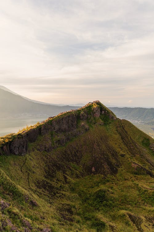 A mountain with a green grassy hill and a green mountain