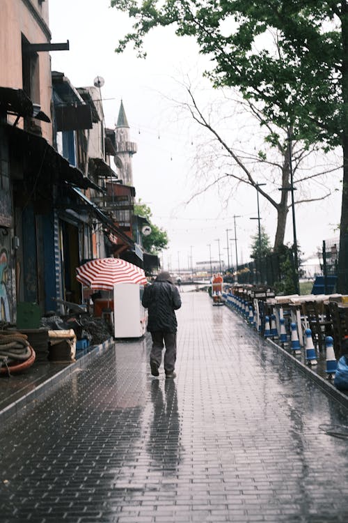 A man walking down a wet sidewalk with an umbrella