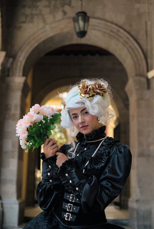 A woman in a gothic costume holding flowers