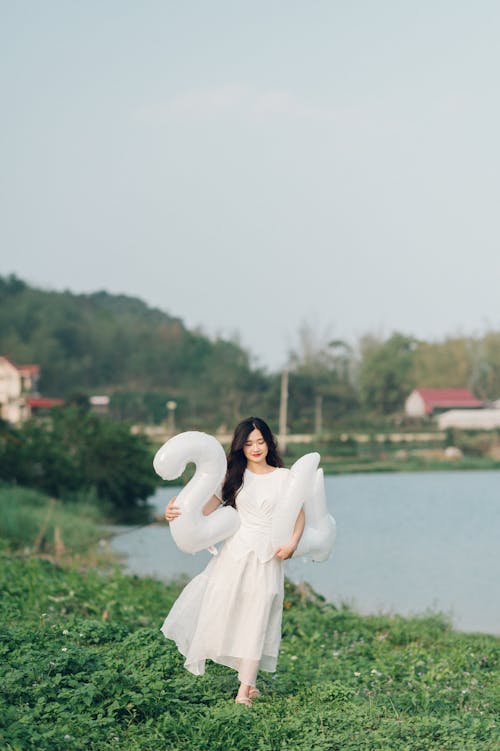 Free A woman in a white dress holding a large white swan Stock Photo