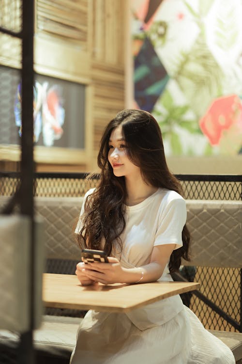 A woman sitting at a table with her phone