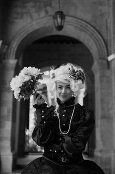 Black and white portrait of an elegant woman in vintage attire holding a bouquet.