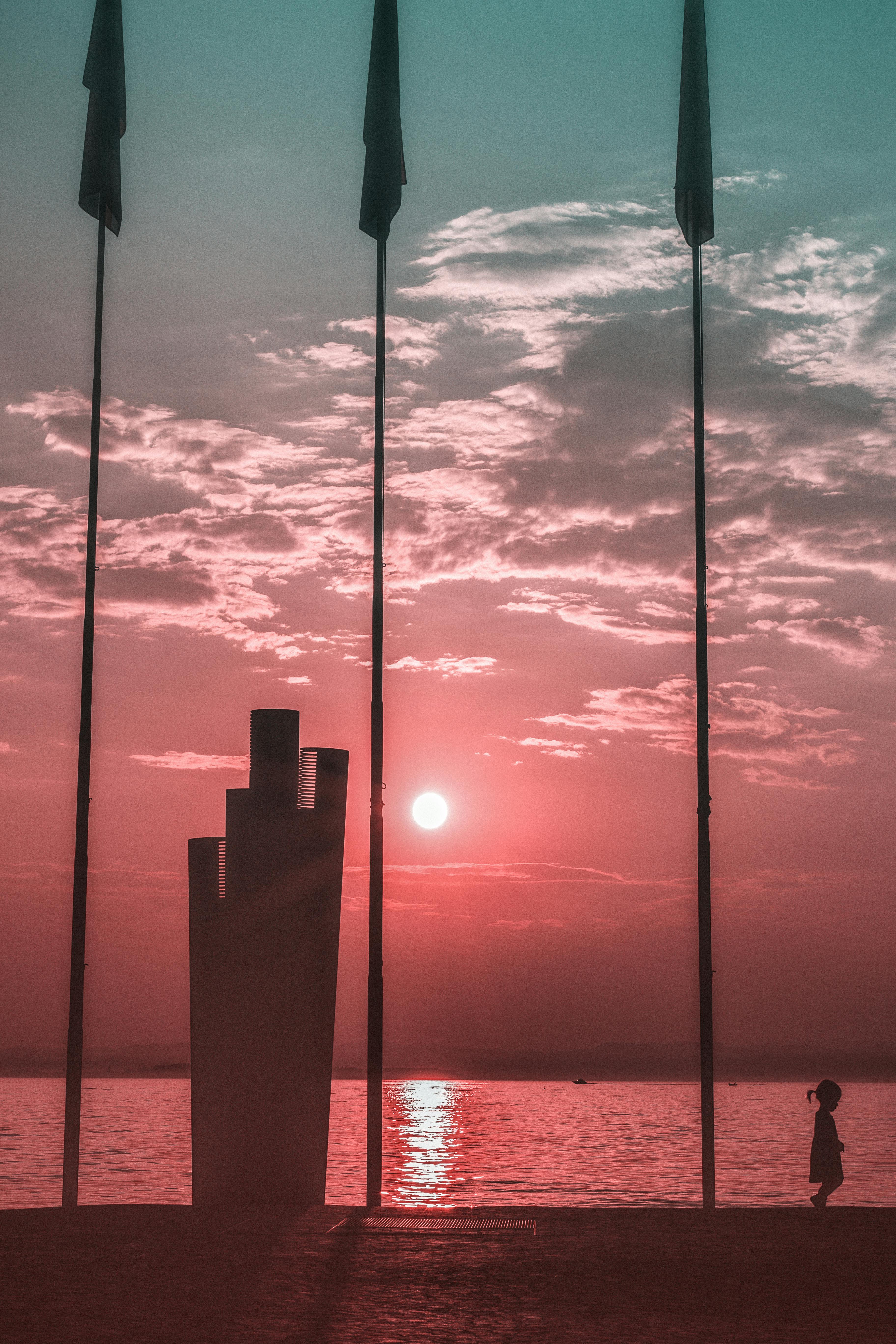 日落时分，一个孩子走在海滩上，天空充满活力，场景宁静