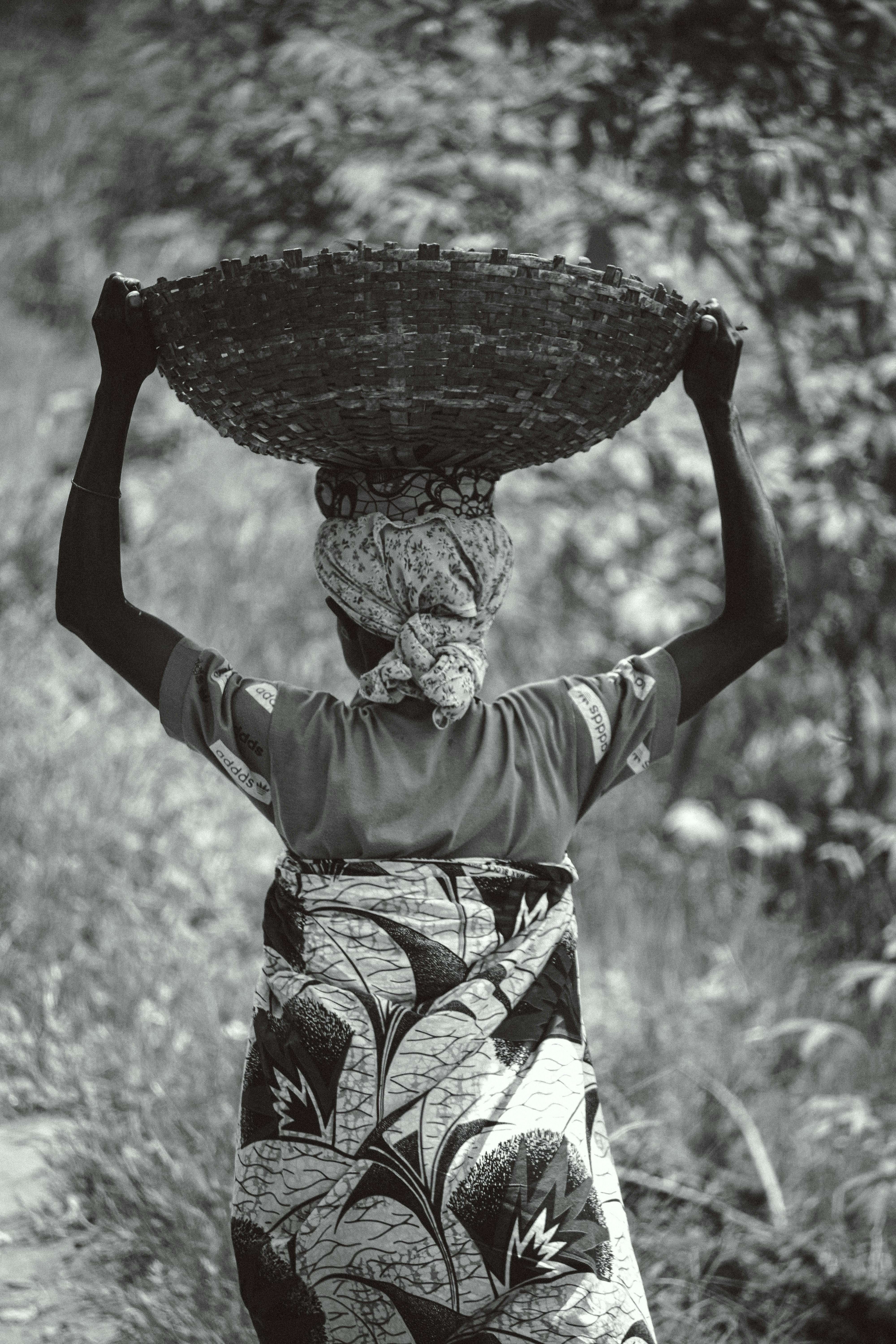 A traditional African woman in rural Burundi carrying a basket on her head.