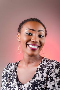 Portrait of a smiling woman with elegant makeup and hoop earrings on a warm background.
