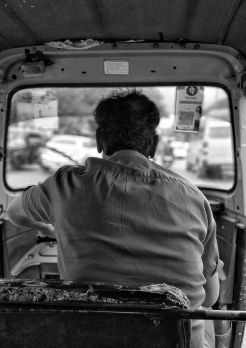 Free Monochrome view from the backseat of a rickshaw with a driver navigating traffic. Stock Photo