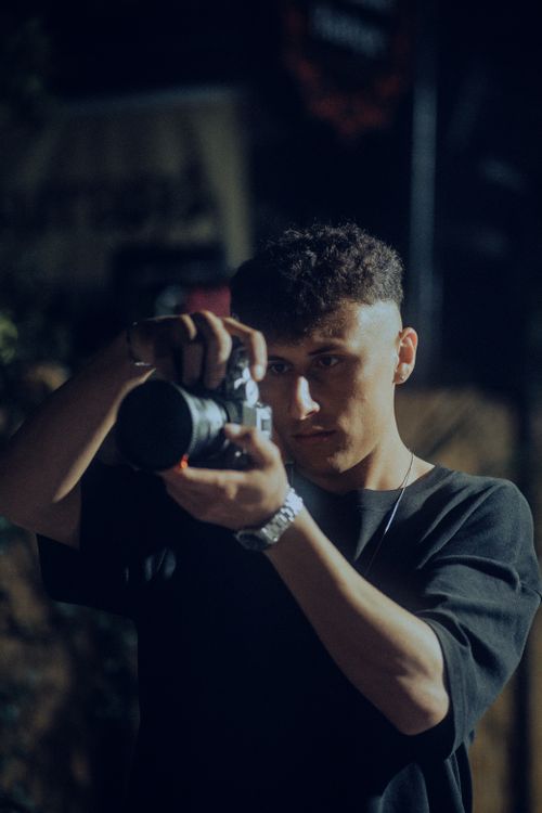 Free Focused young male photographer capturing images at night with a digital camera. Stock Photo
