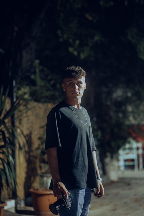 Free Moody street portrait of a young man holding a camera at night. Stock Photo